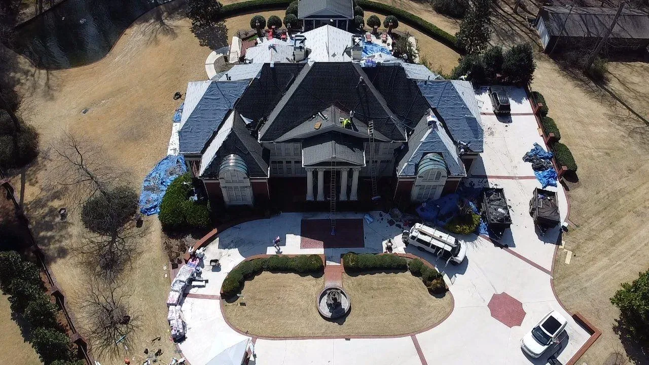 A large North Georgia home mid-reroof with sections tarped after storm damage, a full insurance claim job